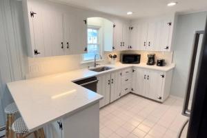 a white kitchen with white cabinets and a sink at Sunshine House steps from Beach in Seabrook