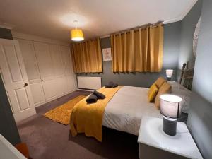 a bedroom with a large bed with a yellow blanket at Lovely Stylish 3 Bed House with Free Parking in Norwich