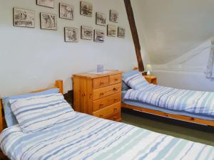 a bedroom with two beds and a dresser and pictures on the wall at October Cottage in Collingbourne Kingston