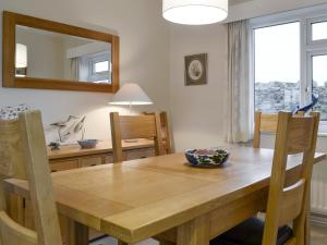 a dining room with a wooden table and a mirror at Craigneish Bungalow in Trearddur