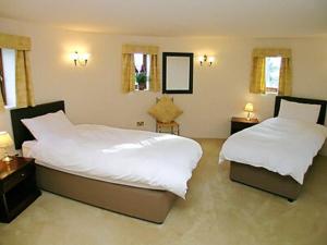 a bedroom with two beds and two tables and windows at Thornsdale Oast House in Stone