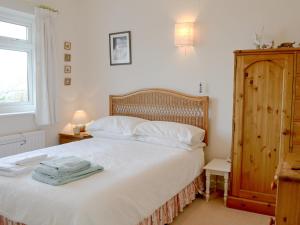 a bedroom with a bed with white sheets and a window at Craigneish Bungalow in Trearddur