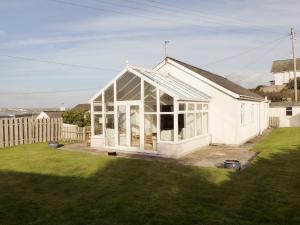 a white house with a greenhouse in a yard at Craigneish Bungalow in Trearddur
