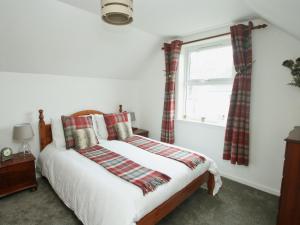 a bedroom with a bed and a window at Mackenzie Cottage in Poolewe