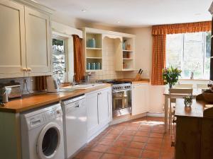 una cucina con armadi bianchi e una lavatrice/asciugatrice di Rose Cottage No2 - 28440 a Chipping Campden