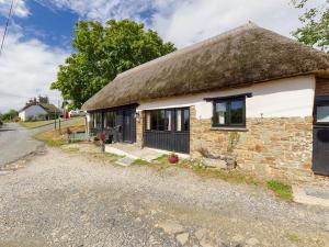 an old stone house with a thatched roof at The Old Coach House in Iddesleigh