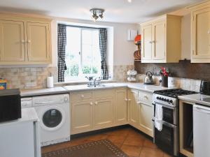 a kitchen with yellow cabinets and a sink at Dragon Fly Cottage in Brompton