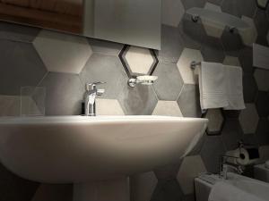 a white sink in a bathroom with a tiled wall at Le dimore di piazza torre in Torchiara +40 photos