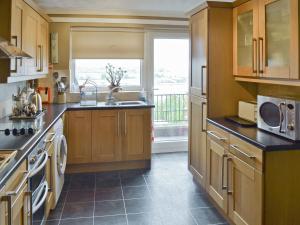a kitchen with wooden cabinets and a sink and a window at Llys Aled in Llanedwen