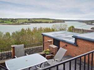 a table and chairs on a balcony with a view of a river at Llys Aled in Llanedwen