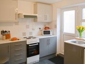 a kitchen with a stove and a microwave in it at Broughs House in Broomhill