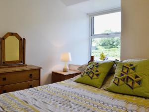 1 dormitorio con cama con espejo y ventana en Capel Fawnog Bach en Talsarnau