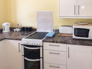 a kitchen with a stove top oven next to a microwave at Manacle View in Saint Keverne