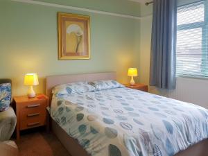 ein Schlafzimmer mit einem Bett, zwei Lampen und einem Fenster in der Unterkunft Sandringham Heights in Paignton