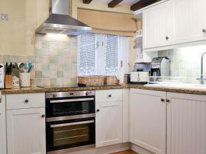 a kitchen with white cabinets and a stove top oven at Mollys Cottage in Knighton
