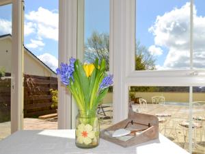 un jarrón de flores sentado en una mesa frente a una ventana en The Little House, en Calstock