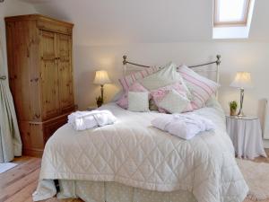 a bedroom with a bed with pink and white pillows at The Little House in Calstock