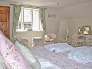 a bedroom with a bed with pink sheets and a window at The Little House in Calstock