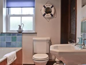uma casa de banho com um WC, um lavatório e uma janela em The Granary em Carperby