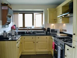 a kitchen with yellow cabinets and a stove top oven at Bwthyn Clyd in Llangollen