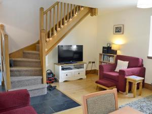 a living room with a staircase and a tv at Bwthyn Clyd in Llangollen