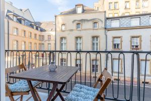 einen Holztisch und Stühle auf einem Balkon mit Gebäuden in der Unterkunft Casa Pestana in Metz