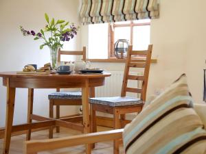 a dining room table and chairs with a vase of flowers at The Hayloft in Great Ormside