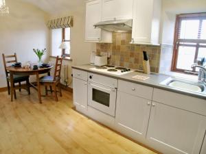 a kitchen with white cabinets and a table and a sink at The Hayloft in Great Ormside