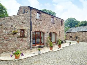 a stone house with potted plants in front of it at The Hayloft in Great Ormside