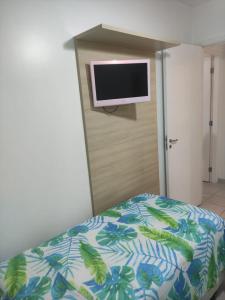 a bedroom with a bed and a tv on a wall at RESERVA DO MAR in Bertioga