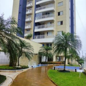 a building with palm trees in front of it at RESERVA DO MAR in Bertioga