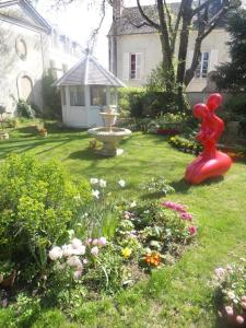 a garden with a red statue in the grass at Le Cedre Bleu in Bourges