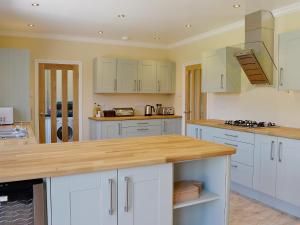 uma cozinha com armários brancos e um balcão de madeira em Clydesdale em North Somercotes
