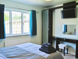 a bedroom with a bed with a mirror and a tv at Clydesdale in North Somercotes
