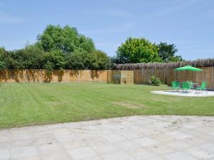 a yard with chairs and a green umbrella at Clydesdale in North Somercotes