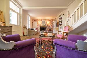 a living room with purple chairs and a fireplace at Le Cedre Bleu in Bourges