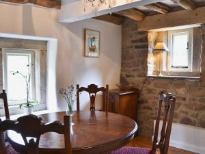 a dining room with a wooden table and a window at Post Office Cottage in Highpeak Junction