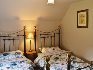 a bedroom with two beds and a lamp at Post Office Cottage in Highpeak Junction