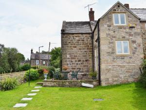 an old stone house with a grass yard at Post Office Cottage in Highpeak Junction