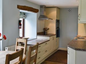 a kitchen with white cabinets and a table with chairs at Higher Paradise in Gisburn