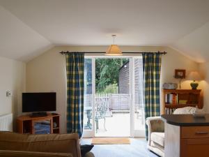 a living room with a tv and a sliding glass door at Bluebell Cottage in Alburgh