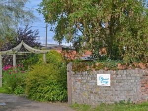 Alburgh的住宿－Bluebell Cottage，砖墙上带有标志的花园