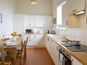 une cuisine avec des placards blancs et une table en bois dans l'établissement Fell Cottage, à Scarborough