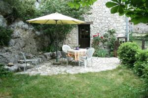 a table and chairs with an umbrella in a yard at Le gite panda saint-maymes in Trigance