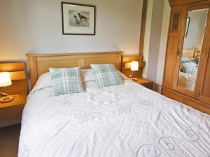 a bedroom with a large white bed with two lamps at Little Gable in Berrington