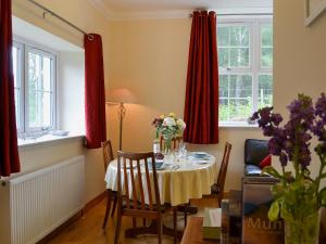 a dining room with a table with flowers on it at Laundry Cottage in Achlain