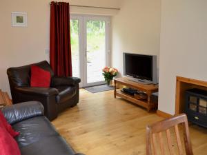 a living room with a couch and a television at Laundry Cottage in Achlain