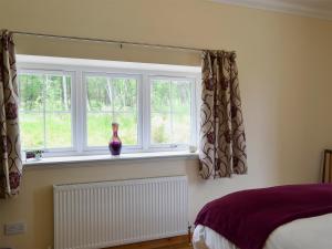a bedroom with a vase sitting on a window sill at Laundry Cottage in Achlain