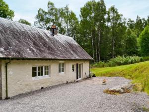 a white house with a roof on a gravel driveway at Laundry Cottage in Achlain