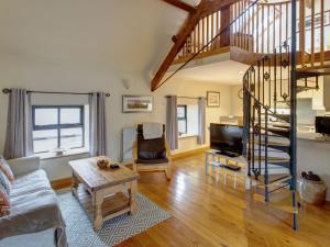 a living room with a spiral staircase and a living room at Corn Cottage in Fenham